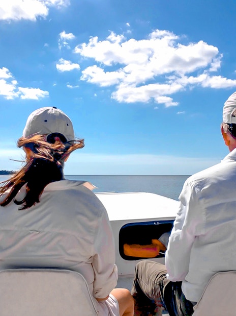Guests on airboat tour in national park, viewing open water and distant trees.