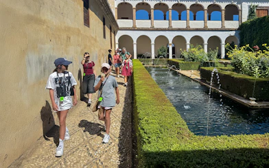 Tourists walking with guide at Alhambra courtyard, Granada, Spain.