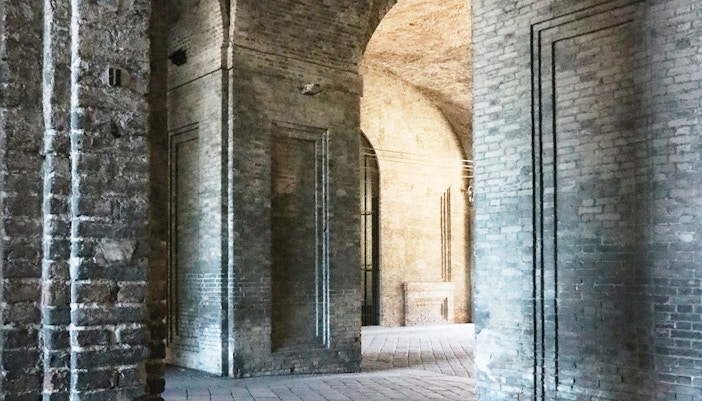 Historic stone passageway in ancient city, with arches and cobblestone path, showcasing architectural heritage.