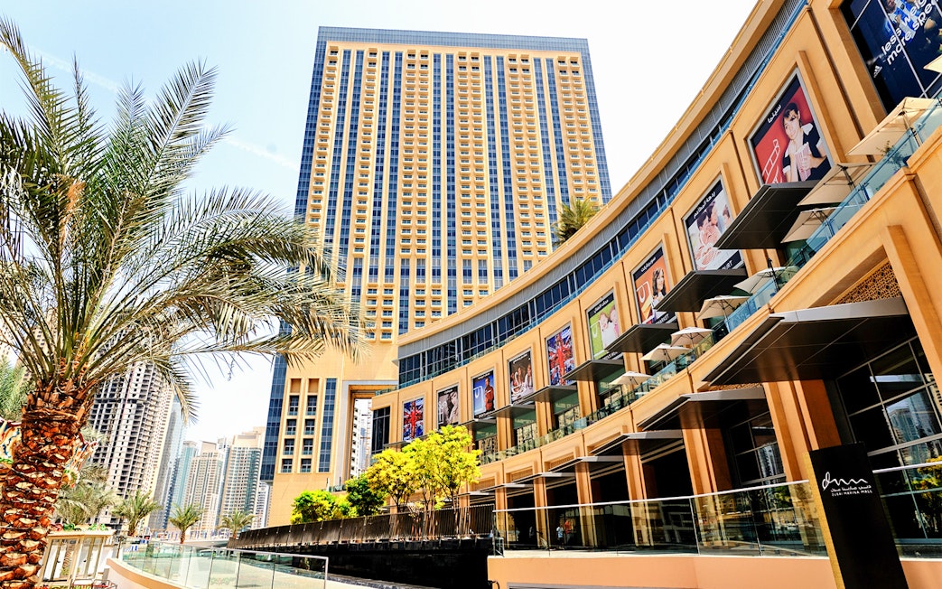 Dubai Mall exterior with palm trees and high-rise buildings in the background.