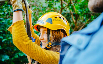 Guest zip lining on Kohala Canopy Adventure, wearing a helmet and harness.
