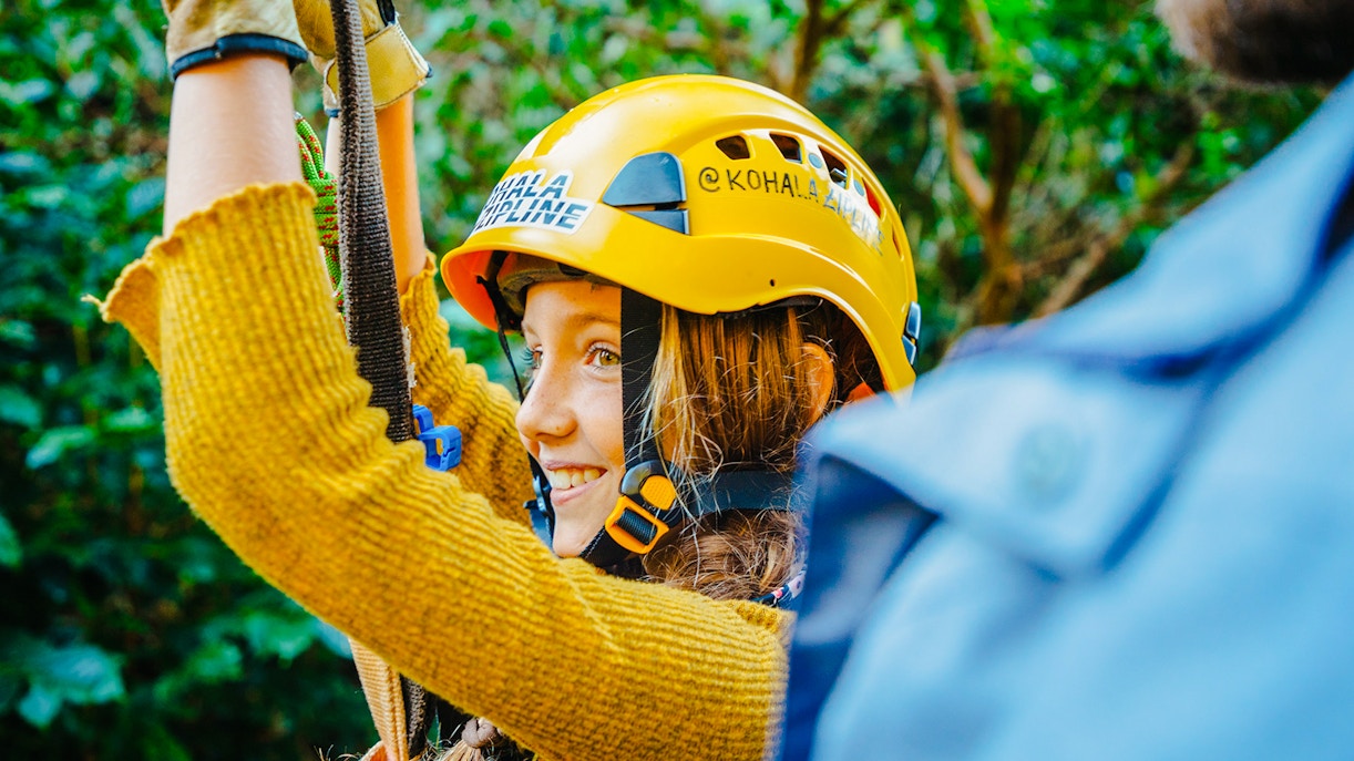 Guest zip lining on Kohala Canopy Adventure, wearing a helmet and harness.