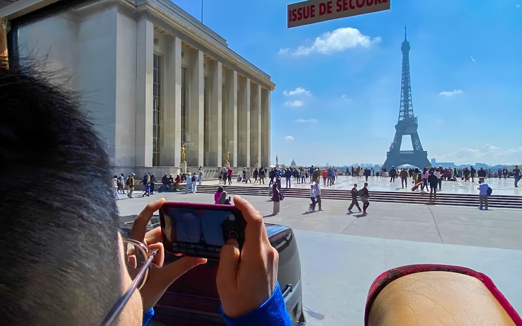 Person photographing Eiffel Tower from Trocadéro, Paris during day trip.