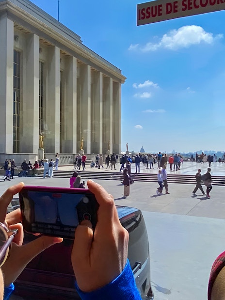 Person photographing Eiffel Tower from Trocadéro, Paris during day trip.