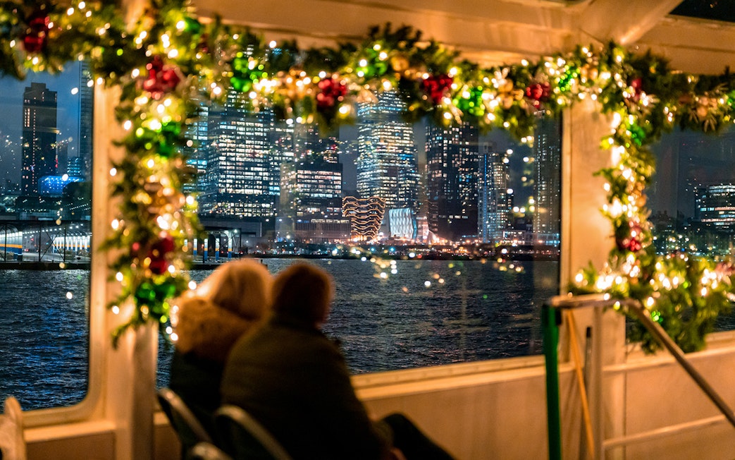 Couple enjoying New York City skyline from decorated boat on Circle Line Harbor Lights Cruise.