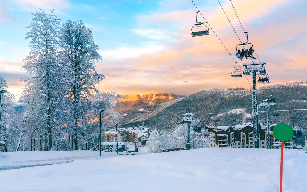 Ski lift ascending snowy mountain at Vivaldi Park Ski Resort with sunset view.