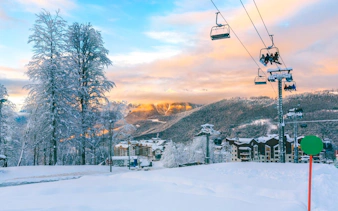 Ski lift ascending snowy mountain at Vivaldi Park Ski Resort with sunset view.