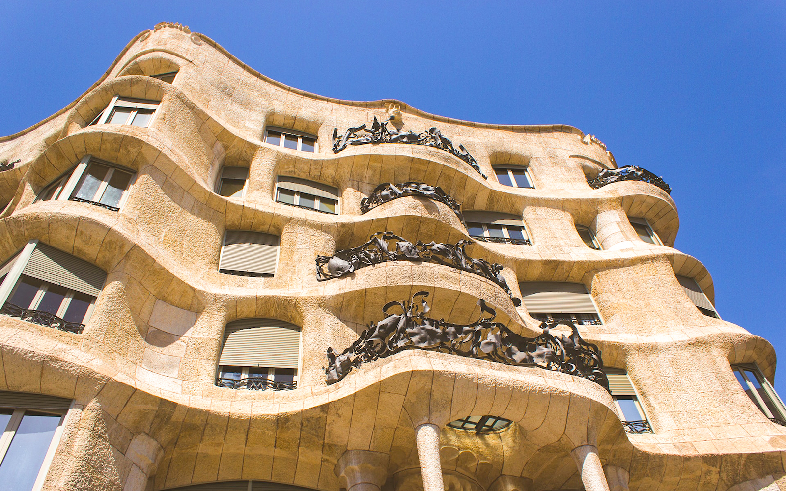 Casa Mila Rooftop with unique chimneys and Barcelona cityscape in the background.