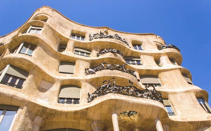 Casa Mila Rooftop with unique chimneys and Barcelona cityscape in the background.