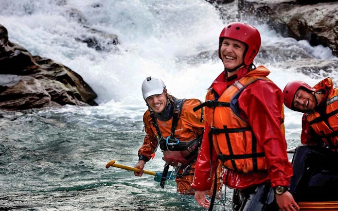 Rafters in gear smiling on Shotover River, Queenstown, during a whitewater rafting adventure.