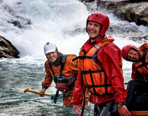 Rafters in gear smiling on Shotover River, Queenstown, during a whitewater rafting adventure.