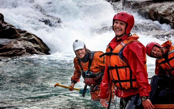 Rafters in gear smiling on Shotover River, Queenstown, during a whitewater rafting adventure.