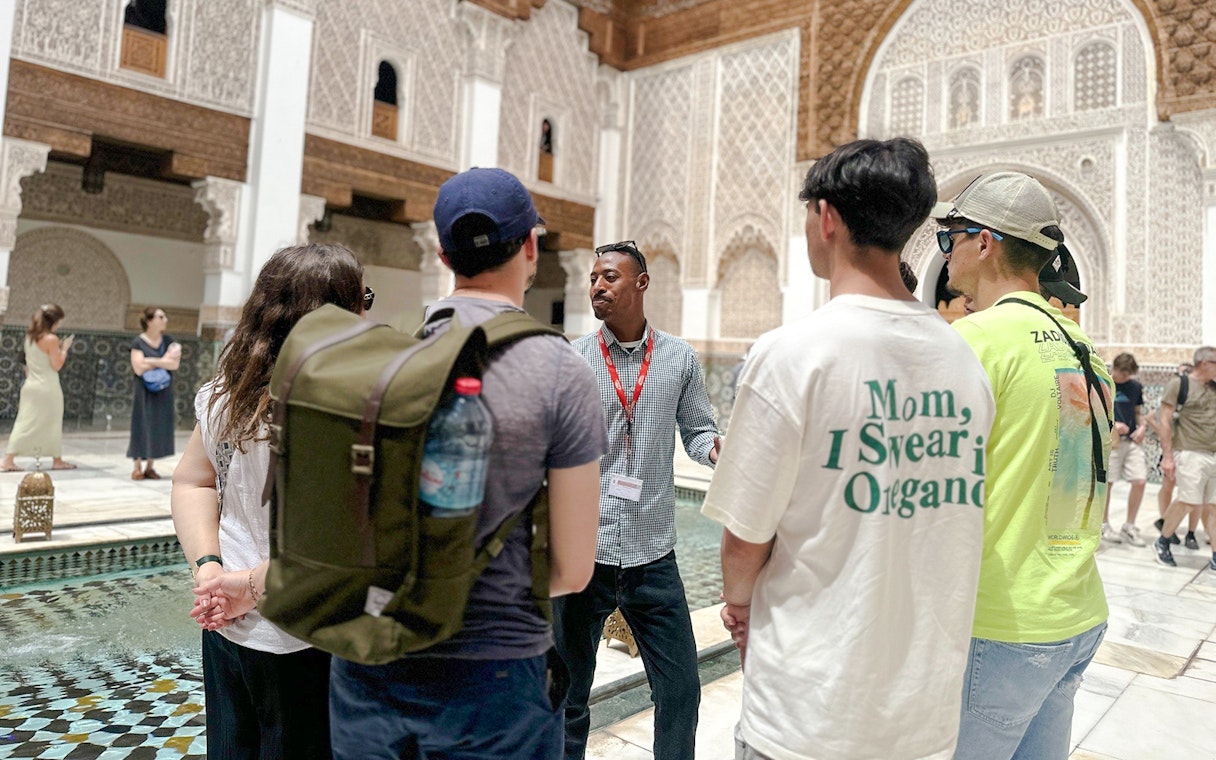 Tourists listening to a guide at Ben Youssef Madrasa in Marrakech, Morocco.