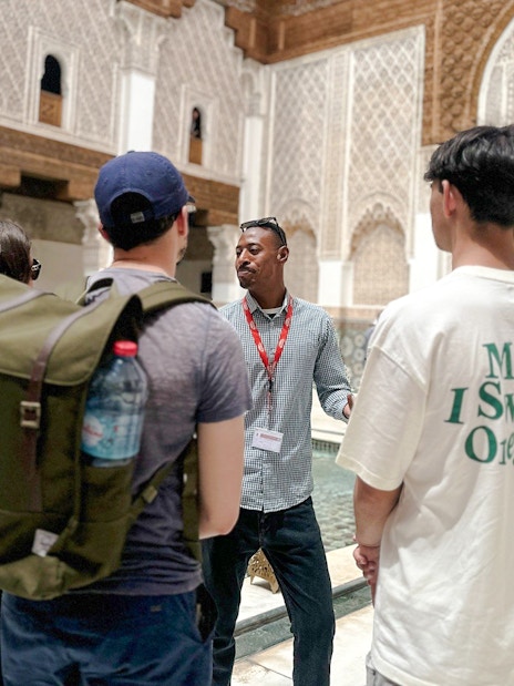 Tourists listening to a guide at Ben Youssef Madrasa in Marrakech, Morocco.
