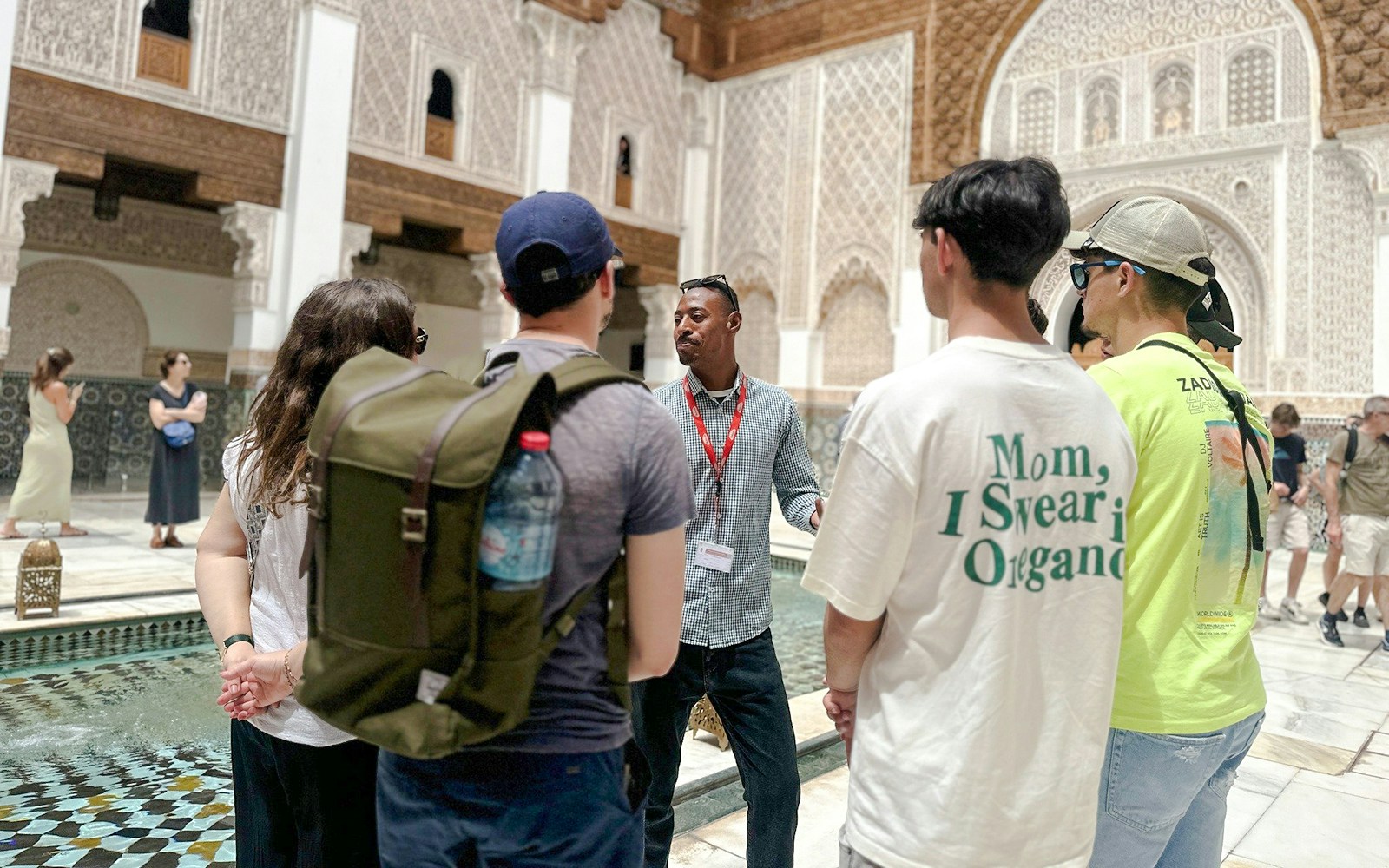 Tourists listening to a guide at Ben Youssef Madrasa in Marrakech, Morocco.