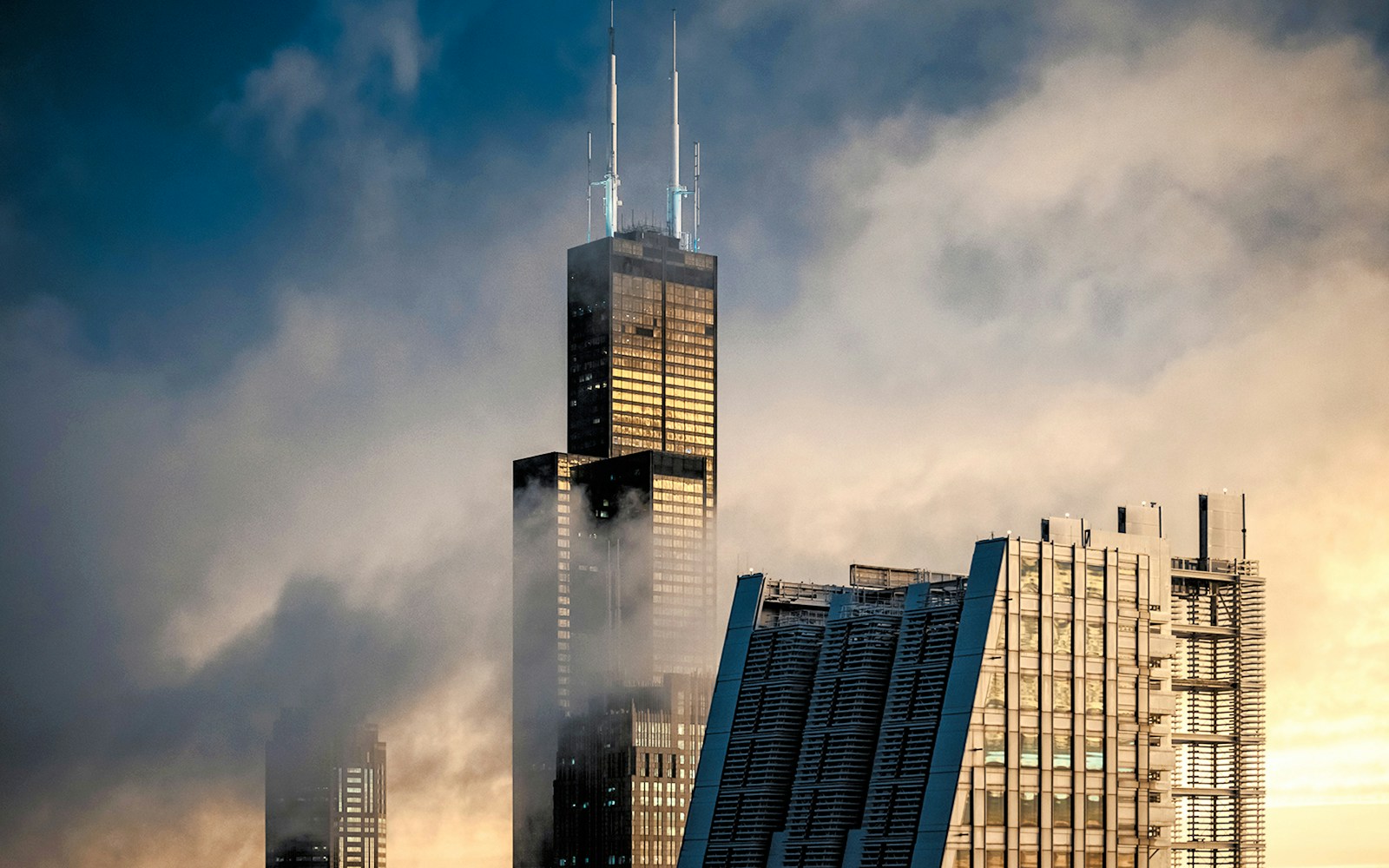 Willis Tower shrouded in mist with raindrops on the window, Chicago skyline in the background.