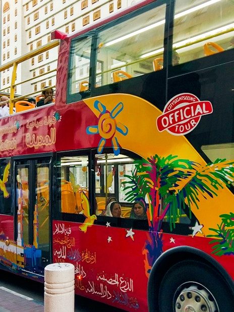 Red double-decker bus on Al Madinah Hop-On Hop-Off Tour with passengers on board.