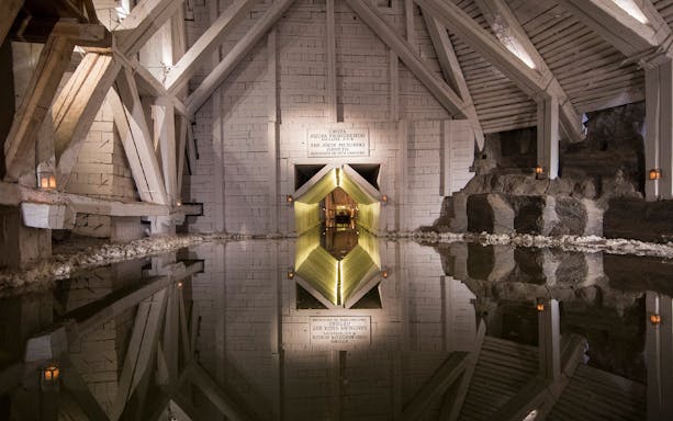 Salt Mine chamber with reflective water and wooden beams, part of Kraków guided tour.