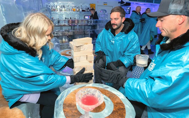 Guests playing Jenga at IceBar Melbourne, wearing blue parkas and gloves.