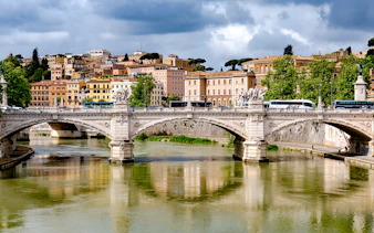 Bridge over river with historic buildings in the background, Rome, Italy.