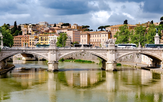 Bridge over river with historic buildings in the background, Rome, Italy.