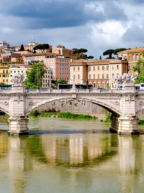 Bridge over river with historic buildings in the background, Rome, Italy.