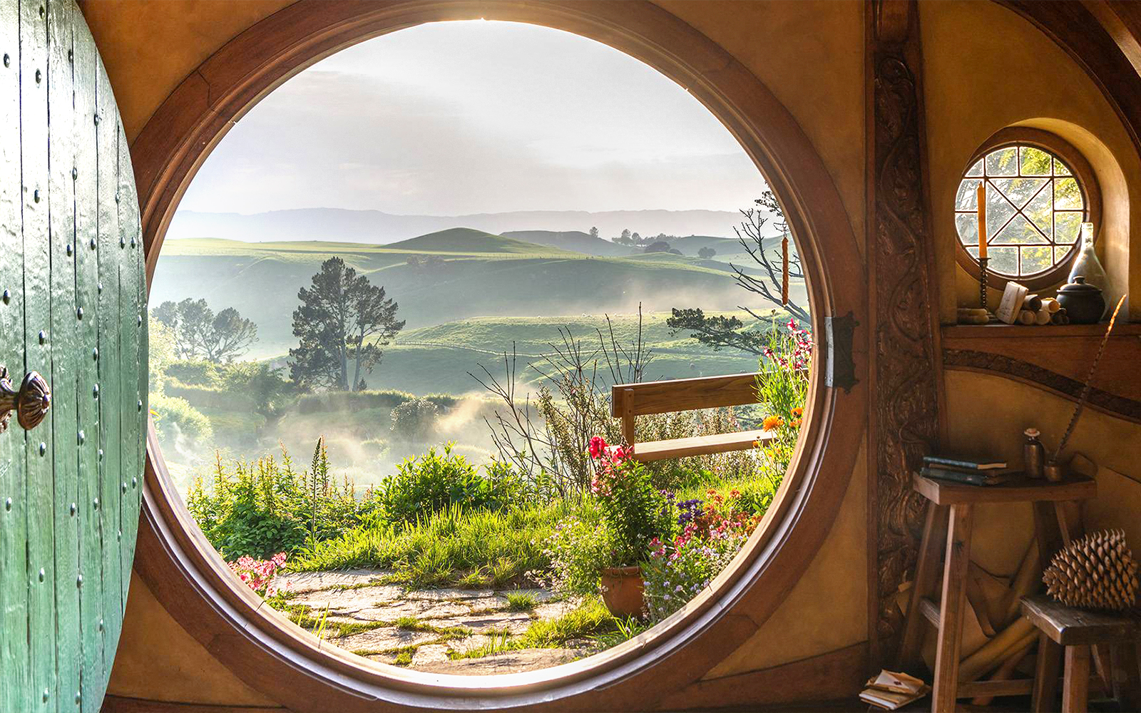 View from Hobbiton house window overlooking lush green hills in New Zealand.