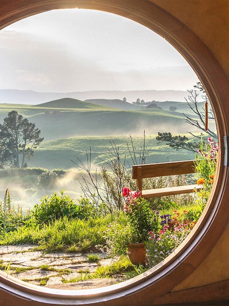 View from Hobbiton house window overlooking lush green hills in New Zealand.
