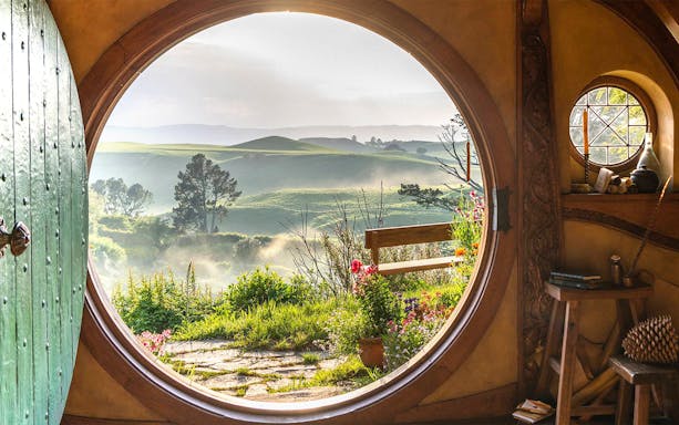 View from Hobbiton house window overlooking lush green hills in New Zealand.