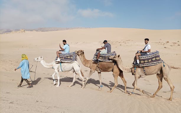 Camel ride in Agadir's Sahara Desert with tourists and guide.