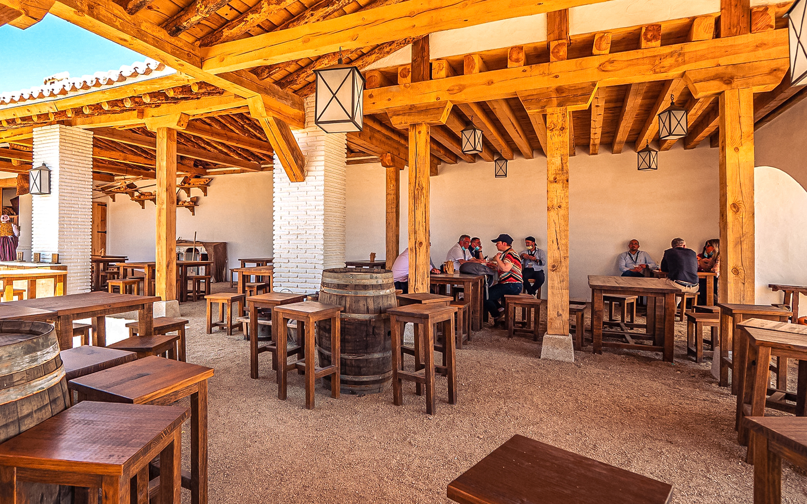 Outdoor dining area with wooden tables and people at Puy du Fou Park.