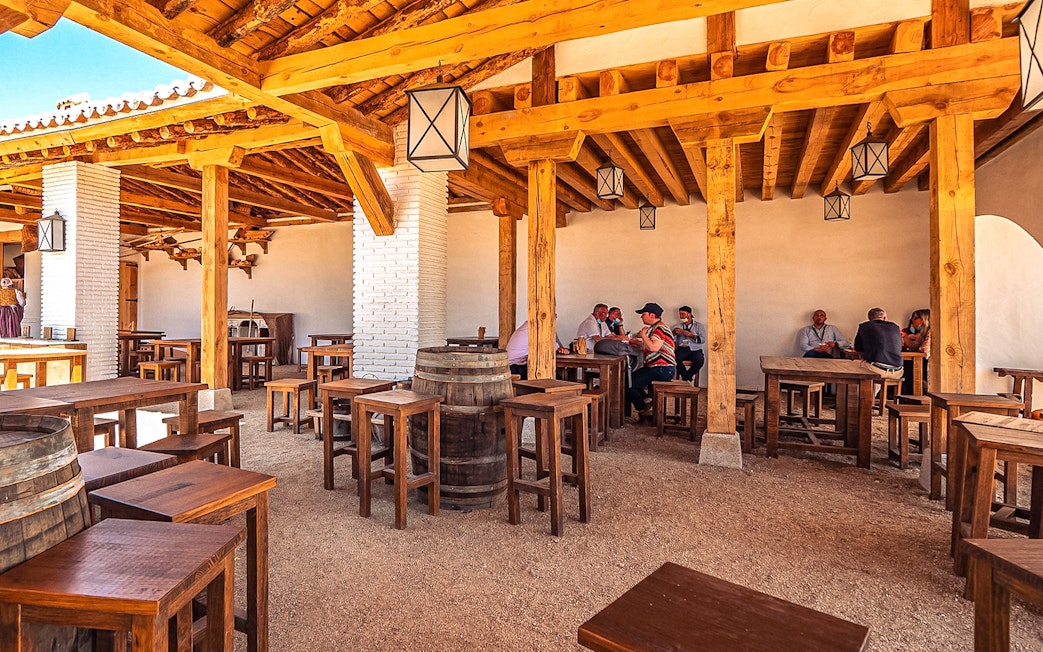 Outdoor dining area with wooden tables and people at Puy du Fou Park.