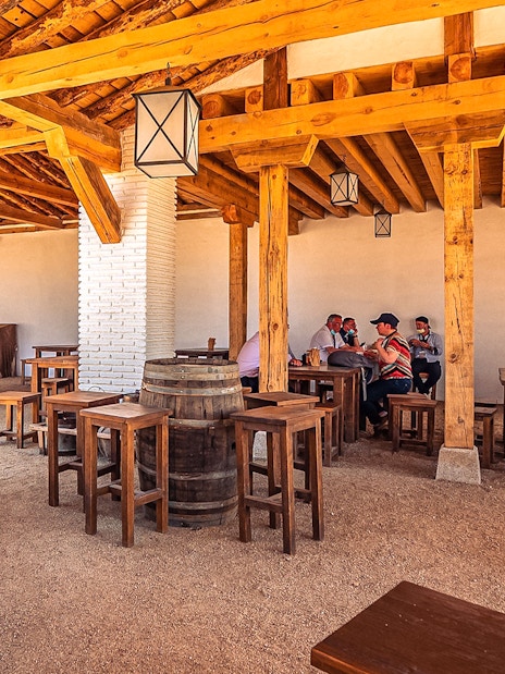 Outdoor dining area with wooden tables and people at Puy du Fou Park.