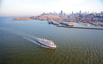 Cruise ship sailing near San Francisco skyline and Bay Bridge.