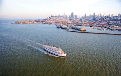 Cruise ship sailing near San Francisco skyline and Bay Bridge.