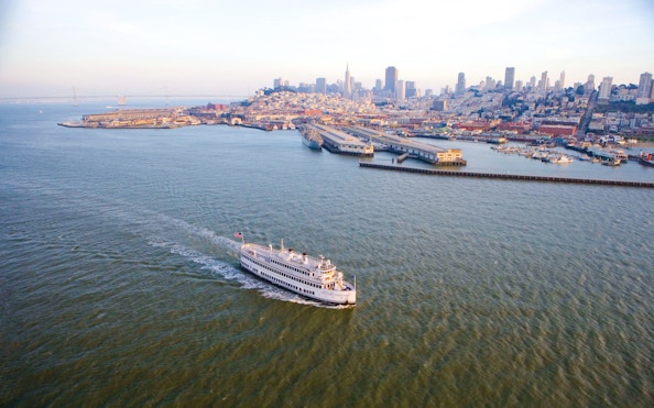 Cruise ship sailing near San Francisco skyline and Bay Bridge.