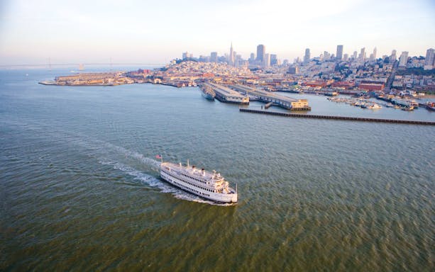Cruise ship sailing near San Francisco skyline and Bay Bridge.