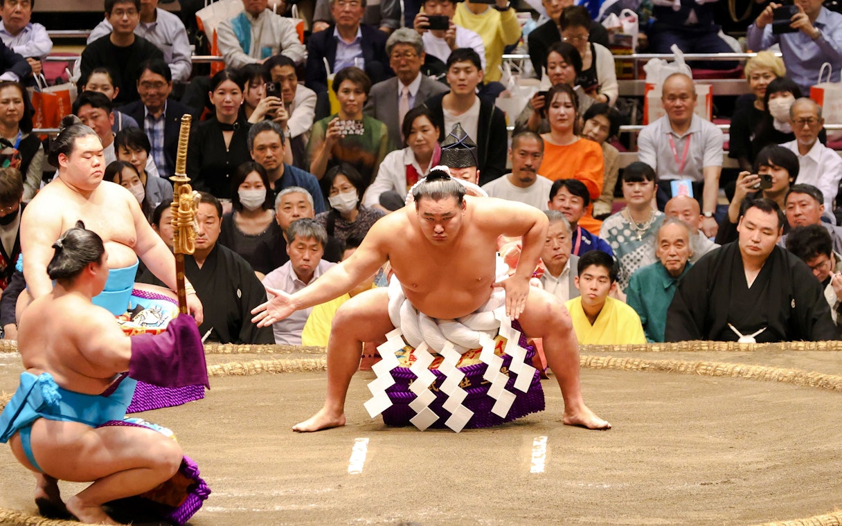 Sumo wrestler performing pre-match ritual in Tokyo ring.