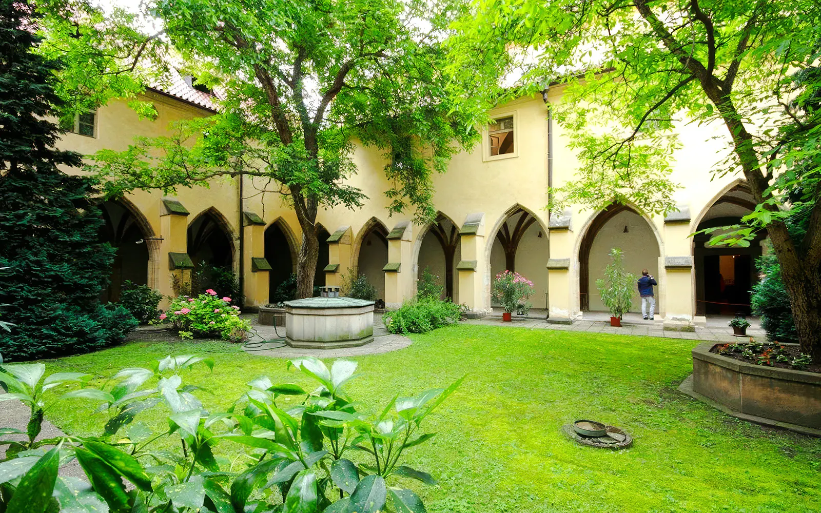 Courtyard of the Minorite Monastery of St. James in Prague with arches and greenery.
