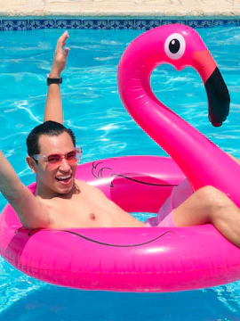 Person enjoying pool on pink flamingo float at Flamingo Beach Club.
