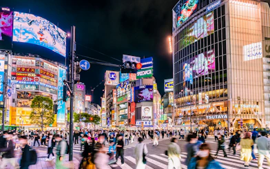 Shibuya Crossing in Tokyo bustling with tourists at night.