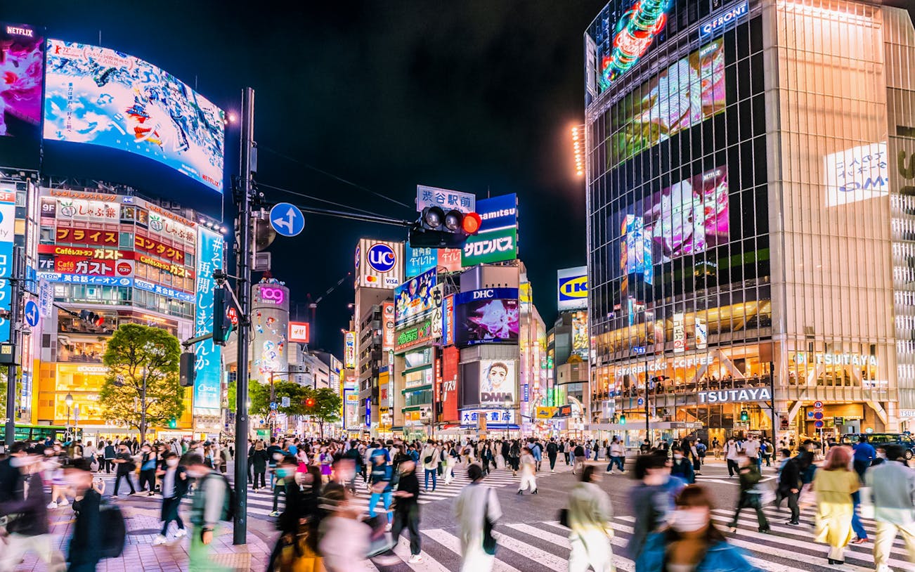 Shibuya Crossing in Tokyo bustling with tourists at night.
