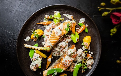 Salmon dish with vegetables and sauce at CÉ LA VI Dubai, featuring Burj Khalifa views.