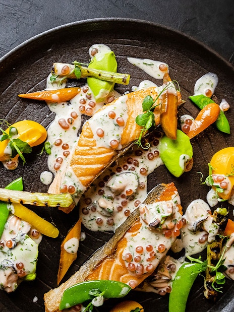 Salmon dish with vegetables and sauce at CÉ LA VI Dubai, featuring Burj Khalifa views.