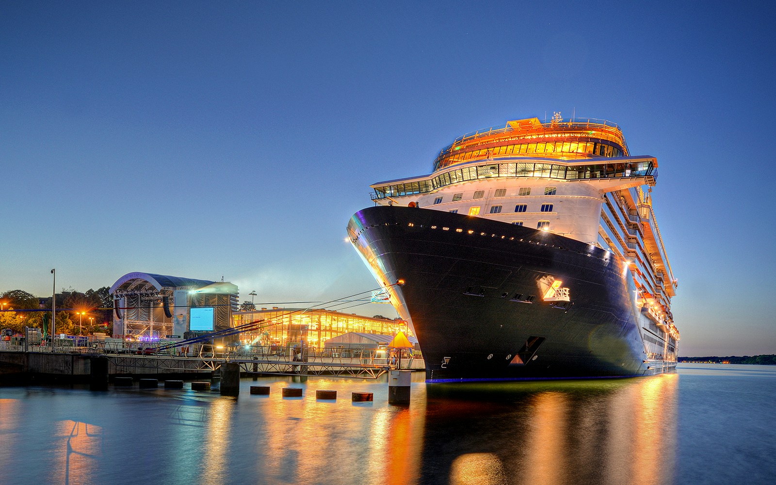 Evening cruise ship on Elbe River with Hamburg skyline in background.