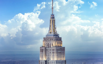 Empire State Building spire against a cloudy sky, New York City.