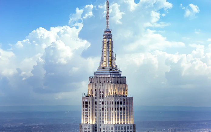 Empire State Building spire against a cloudy sky, New York City.