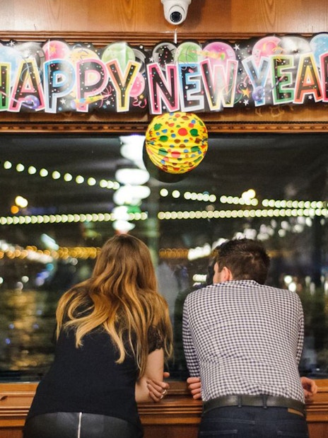 Couple enjoying New Year’s Eve cruise view in Budapest with festive decorations.