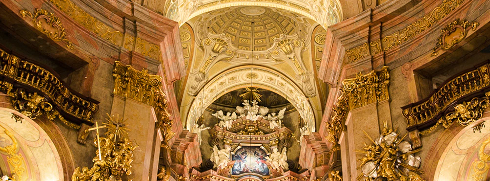 Baroque interior of St. Peter's Church in Vienna with ornate altar and frescoed dome.