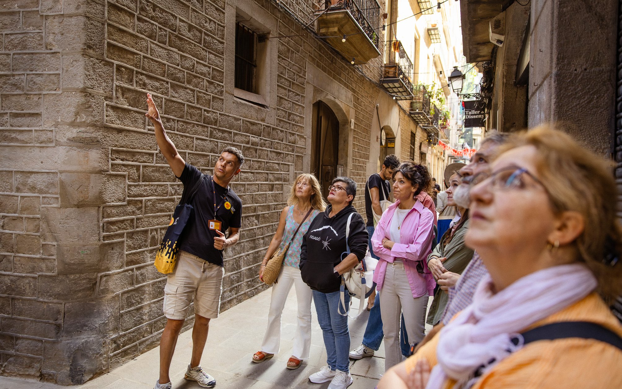 Tourists listening to a guide in a narrow street during a walking tour in Barcelona.